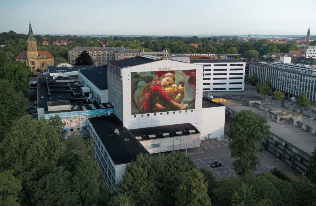 Aalborg Kongres & Kultur Center set skråt oppe fra med stort gavlmaleri på scenetårnet.